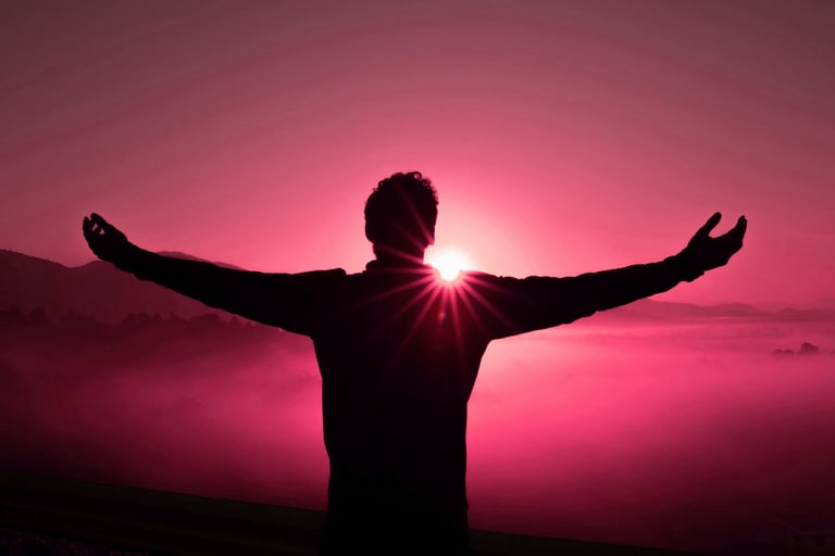 A man stretches his arms wide in the glow of a setting sun