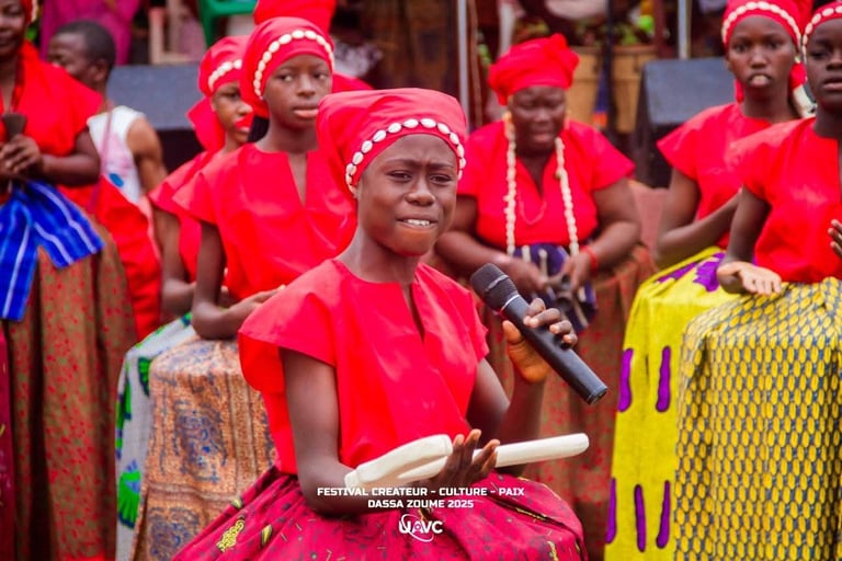 Young Benin singer performing in red traditional attire at the Dassa Zoume 2025 cultural festival.