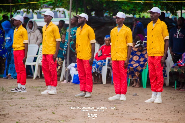 Performers in yellow shirts and red pants at the Festival Createur Culture Paix in Dassa-Zoume 2025.