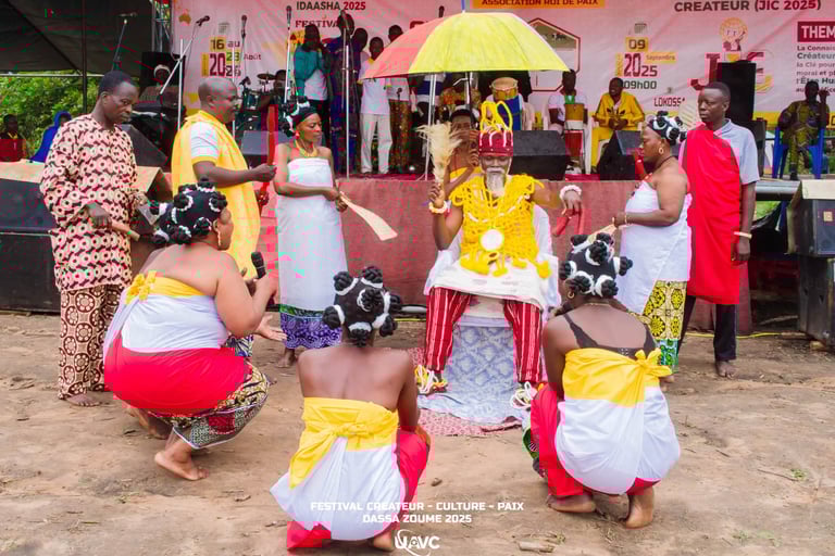 A traditional West African cultural ceremony in Dassa-Zoume featuring a seated King and dancers in tribal attire.