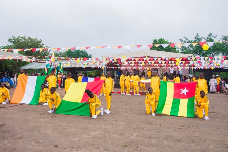 Students in yellow tracksuits hold flags of African nations during an outdoor cultural festival ceremony.