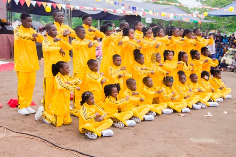 A youth dance troupe wearing matching yellow tracksuits performs a synchronized routine at an outdoor festival.