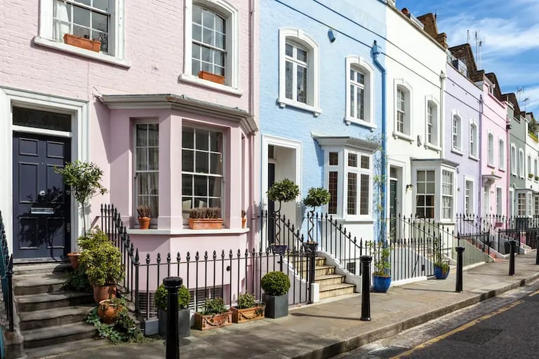 Colorful pastel terraced houses in a charming London neighborhood street with classic bay windows.