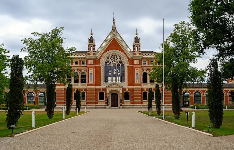 Gothic Revival architecture of Dulwich College red brick building with green trees and gravel path.