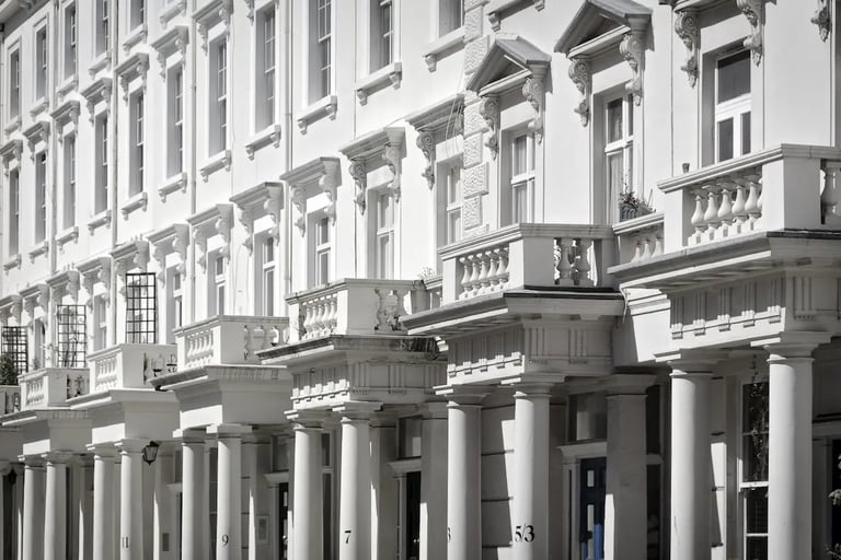 Elegant white Victorian terraced houses in London with classic stucco architecture and pillars.