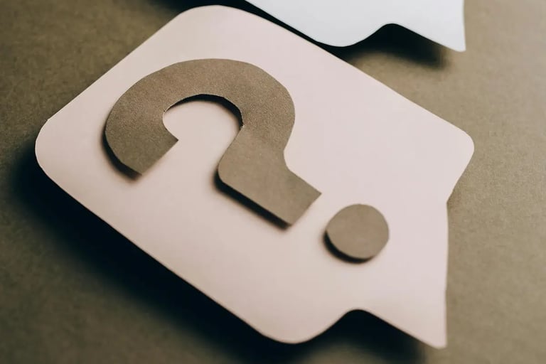 Paper speech bubbles with question marks on a grey background for customer support and FAQ concepts.