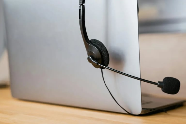 Professional call center headset with microphone resting on a silver laptop for remote work support.
