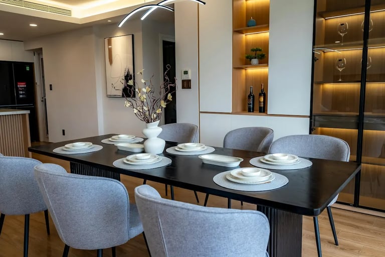 Modern dining room featuring a black table, gray upholstered chairs, and elegant table settings with minimalist decor.