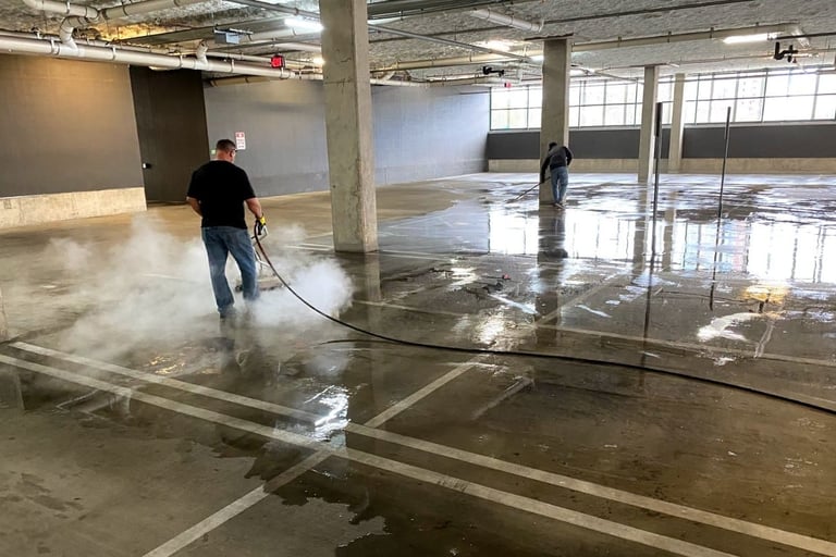 A man pressure washing a commercial garage