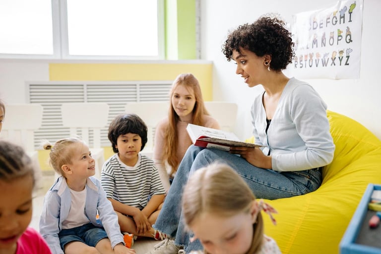 Maestra sonriente leyendo un libro de cuentos a niños en edad preescolar sentados en el suelo del au