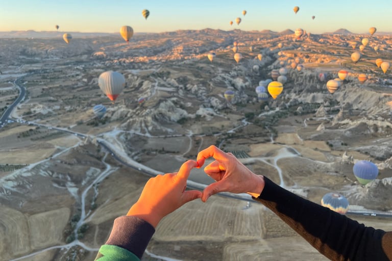 a group of hot air balloons flying over a valley in summer
