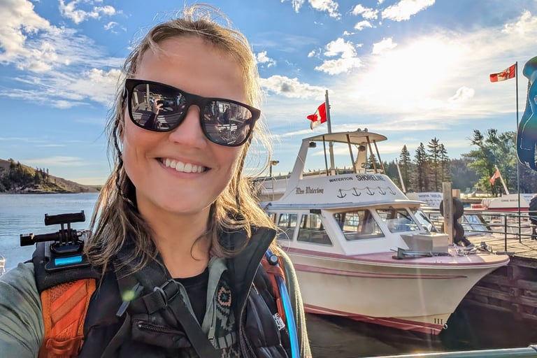 Woman smiling in front of the Miss Waterton shuttle boat before hiking Crypt Lake in Waterton Lakes