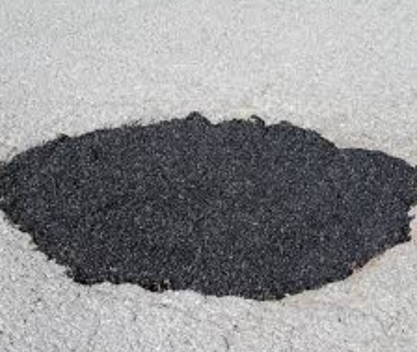 Fresh asphalt patch filling a pothole on a grey pavement road for driveway repair.