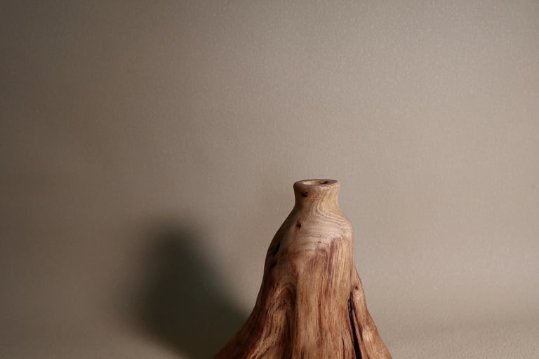 Minimalist wooden sculptures displayed on a white marble fireplace mantel with decorative molding.