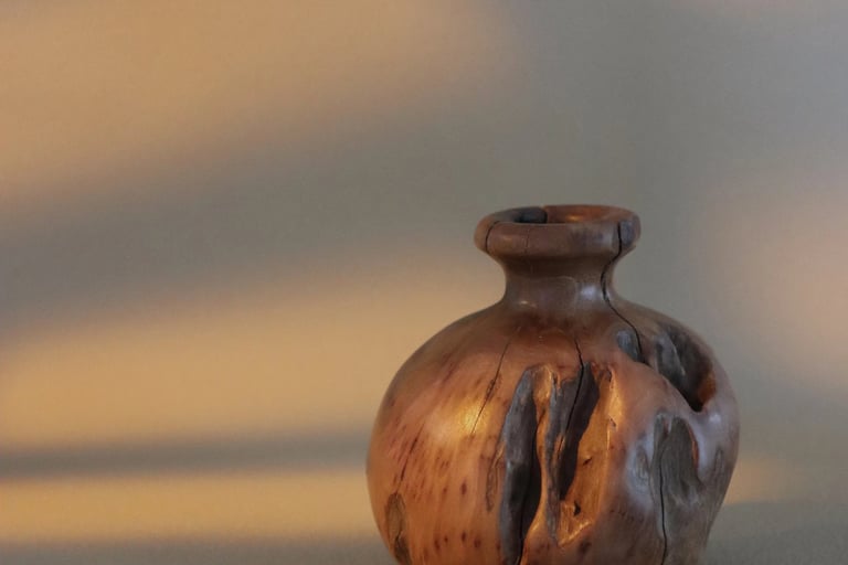 Handcrafted rustic wooden vase with natural bark texture and warm sunlight shadows.