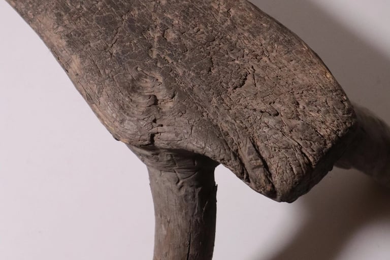 Rustic antique hand-carved wooden stool with weathered texture and organic three-legged design.