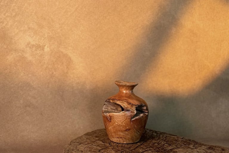 Handcrafted rustic wooden vase displayed on a live edge wood slice with warm natural lighting.