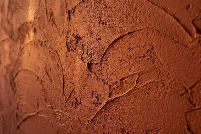Textured reddish-brown clay plaster wall with visible trowel marks and earthy stucco finish.