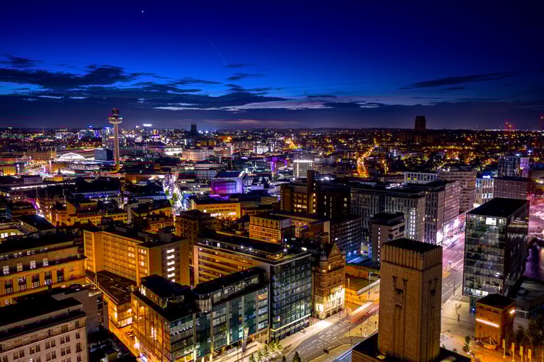 Elevated night view of the illuminated Liverpool city skyline featuring St Johns Beacon and modern urban architecture.