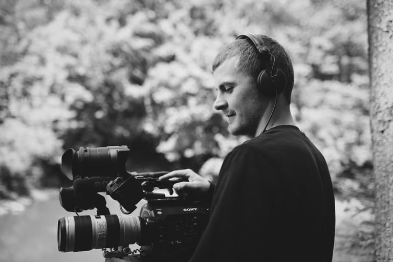 Mann mit Filmkamera im Wald - Aldan Kosnick mit Sony Kamera und Kopfhörern