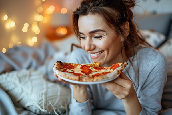 Mujer comiendo piza en el sofá y ensuciándolo