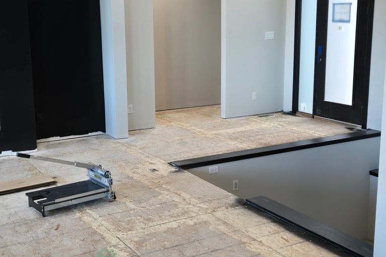 A vinyl plank floor cutter sits on a subfloor during a modern home interior renovation.