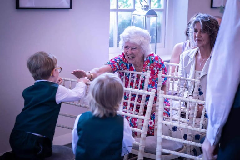 Smiling grandmother high-fiving young page boy at Bury St Edumnds Regsitry Office wedding ceremony.