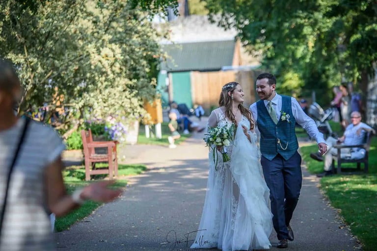 A happy bride and groom walking together in Abbey Gardens Bury St Edmunds.