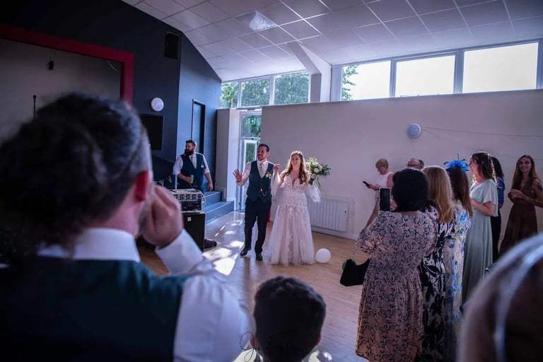 A bride and groom making their entrance at their wedding reception with guests watching.