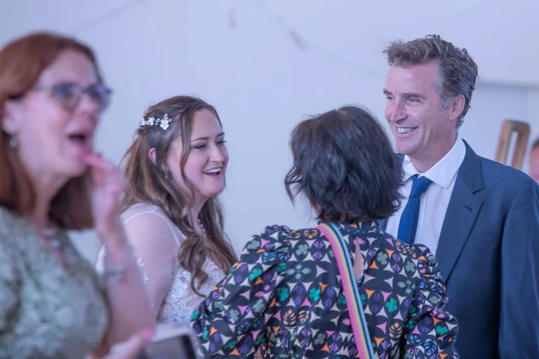 Smiling bride chatting with guests at a wedding reception indoors.