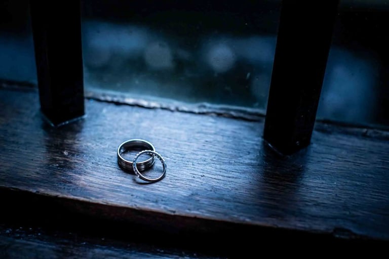 Wedding rings on a dark rustic wooden surface.