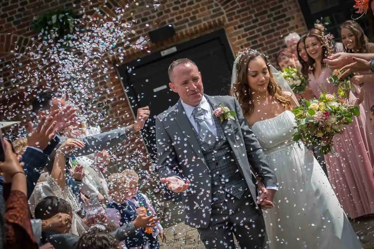 newly-wed running through confetti being thrown by guests