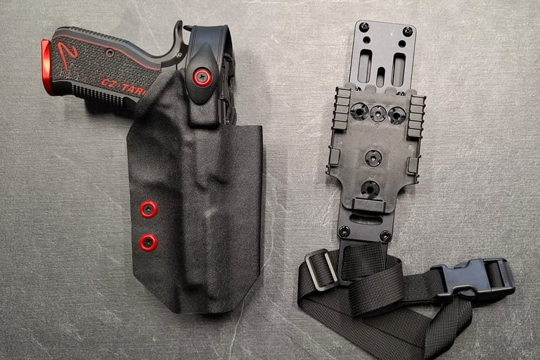 Custom black Kydex holster with red accents holding a CZ Shadow 2 pistol next to a tactical drop leg platform.