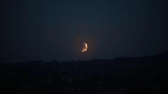The crescent moon shining brightly in a darkened sky.