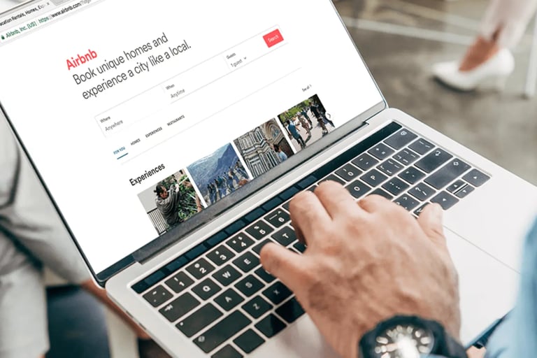 A person using a laptop to browse the Airbnb website for vacation rentals and travel experiences.