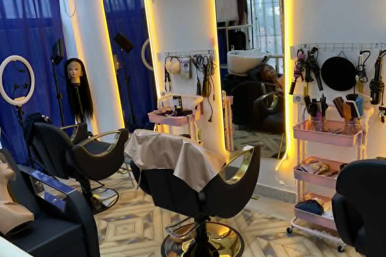 Interior moderno de salão de beleza com espelhos iluminados e cadeiras de atendimento.