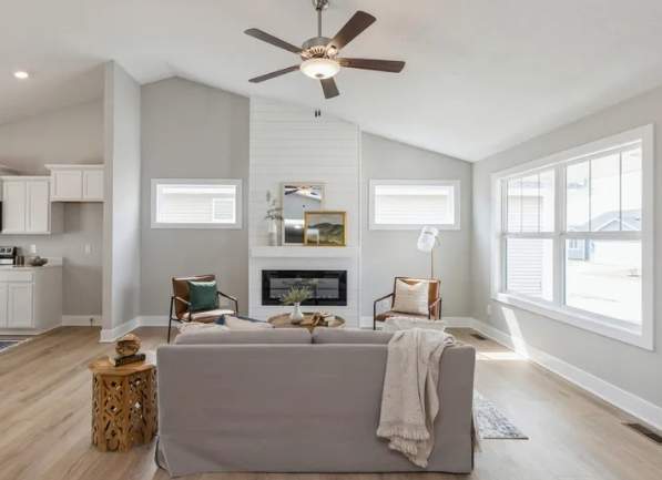 Living room with a fireplace, seating area, and ceiling fan.