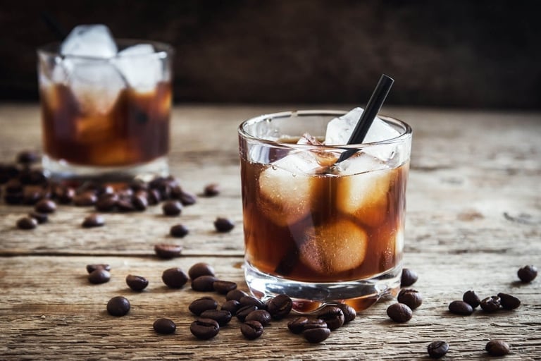 copo com bebida de cafe em cima de uma base de madeira com grãos de cafe