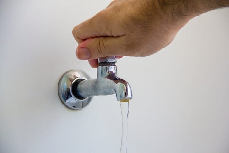mão fechando torneira d'agua