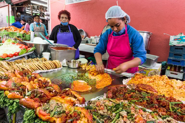 Street food vendors preparing authentic pambazos and tacos on a large griddle at a Mexican market.