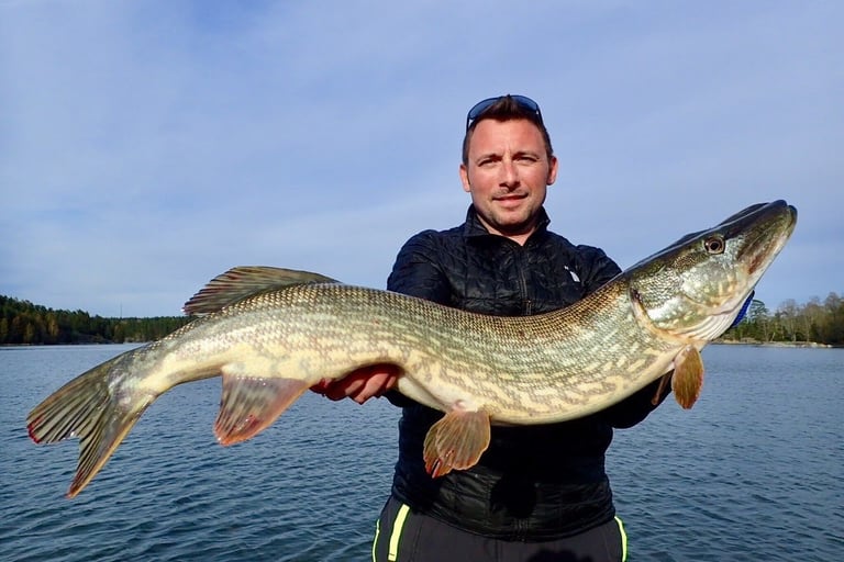 En man är på en båt, han fångade en stor gädda i Sverige tack vare fishing escape sweden..