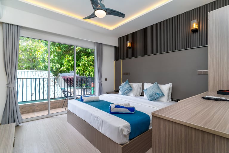 Modern hotel room with king bed, balcony view, and contemporary interior design.