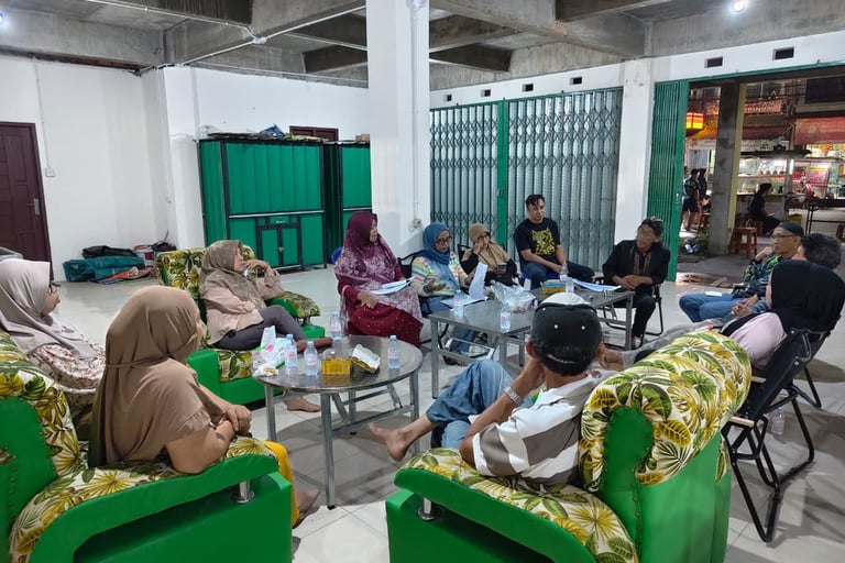 Community members holding a formal neighborhood meeting in a large room with green patterned chairs.