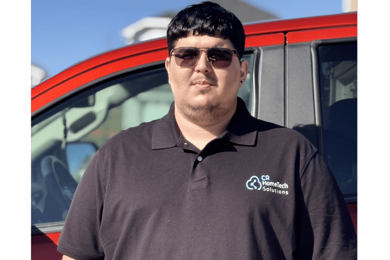 CR HomeTech Solutions technician in a black polo shirt standing in front of a red service vehicle.