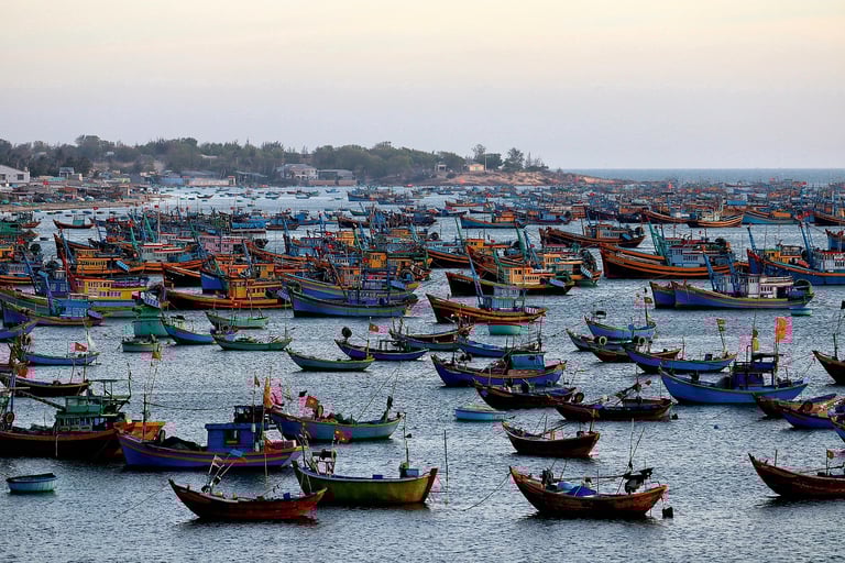 Hundreds of teal and blue wooden fishing boats anchored in the Mui Ne fishing village harbor during