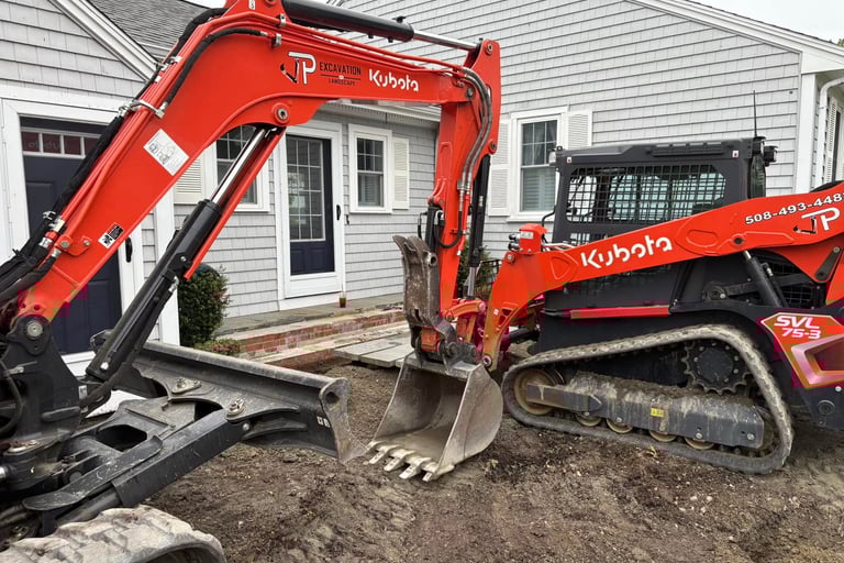 A Kubota mini excavator and SVL 75-3 skid steer perform residential excavation for a new patio.