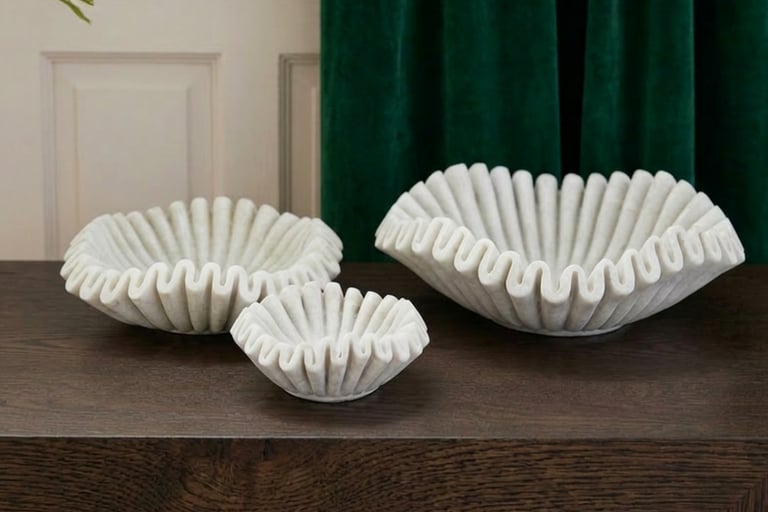Handcrafted white marble bowls styled on dark oak table with deep green velvet curtains in a luxurious organic interior