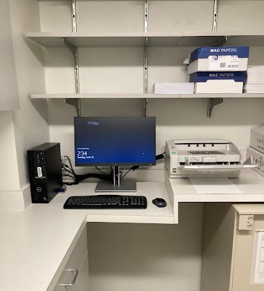 Office workstation with a desktop computer, monitor, keyboard, and printer on a white desk with shelves.