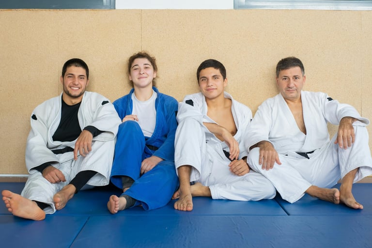 Group of Brazilian Jiu Jitsu participants sitting on the ground smiling