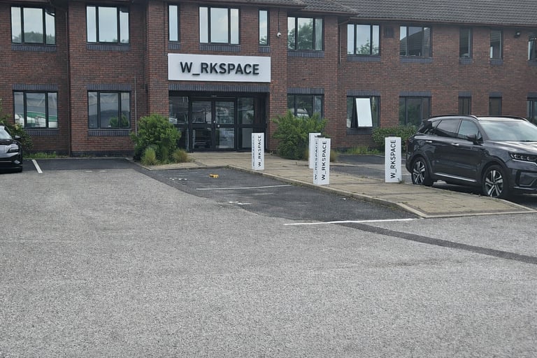 W_RKSPACE shared office building entrance with brick facade and parking lot.